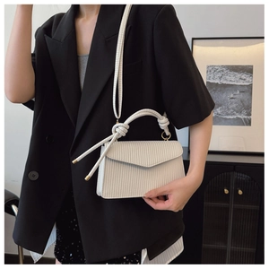 Détail du sac carré blanc tressé avec poignée à nœud et bandoulière amovible
