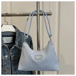 Detail of light blue pleated fabric on tote bag with leather logo and thin rope straps