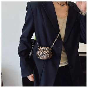 Close-up of leopard print saddle bag with gold chain strap on a chic blazer outfit