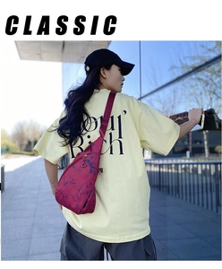 Outdoor street shot of a red tie-dye nylon sling bag worn by a model in a city setting