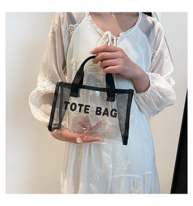 Detail view of a transparent PVC tote bag with black mesh siding and top handles