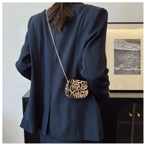 Nahaufnahme einer Mini-Satteltasche mit Leopardenmuster und goldener Kette am Model