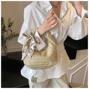 Détail d'un sac hobo en paille tressée avec un foulard décoratif en soie vintage