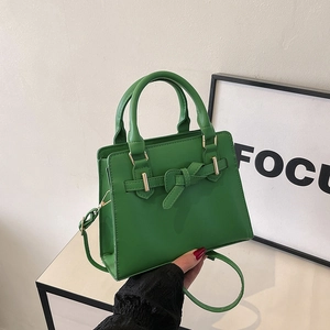 Elegant green handbag with leather bow buckle and crossbody strap for a stylish summer look