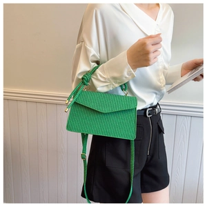 Gros plan d'un sac carré tressé vert vif avec poignée supérieure et fermoir doré chic