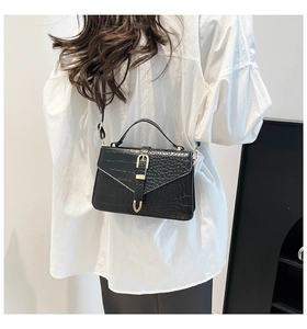 Detailed back view of a black crocodile-textured handbag with gold hardware and strap