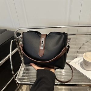 Modern black and brown leather bucket bag with silver buckle held in a stylish setting