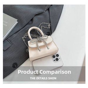 Détail du mini sac crème avec nœud en strass et chaîne à côté d'un smartphone