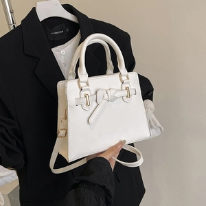 Chic white leather handbag with belt buckle and bow detail, crossbody and top handle style