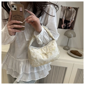 Detailed embroidery of gold butterflies on a cream-colored pleated shoulder bag