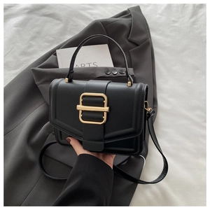 Détail d'un sac bandoulière vintage en cuir noir avec une boucle dorée et une poignée
