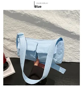 Detail of light blue quilted nylon crossbody bag featuring double front flap pockets