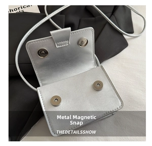 Detail of silver flap crossbody bag showing the dual magnetic snap button closure