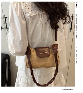 Détail du sac sous le bras en toile et cuir marron porté avec une robe en dentelle