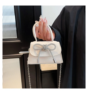 Close-up of cream white PU leather handbag with a sparkling rhinestone bow detail