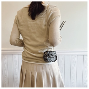 Schicke Mini-Satteltasche mit Leopardenmuster und Goldkette am Outfit des Models