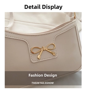 Detail of beige shoulder bag featuring a decorative golden bow metal buckle