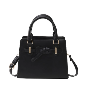 Minimalist black tote bag with bow detail and gold hardware on white background