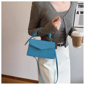 Détail d'un sac à main bleu vif tissé avec poignée à nœuds et bandoulière amovible élégante