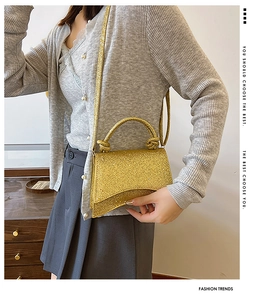 Détail du sac à main doré à paillettes avec base incurvée en sablier et poignée à nœuds