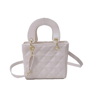Elegant beige quilted mini handbag with gold hardware and top handle in a front view