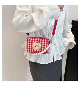Detail of red checkered bag with apple embroidery, pearl chain, and leather strap