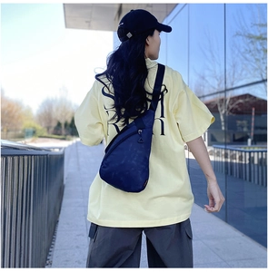 Outdoor shot showing the dark blue nylon sling bag worn as a crossbody backpack