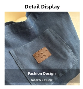 Detail of dark blue denim tote bag featuring a square outer pocket and brown leather patch