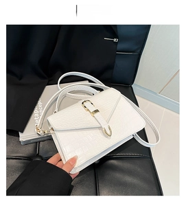 Détail d'un sac à main blanc motif crocodile avec boucle dorée et anse supérieure