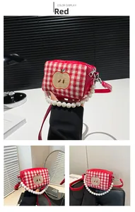 Detailed view of red plaid crossbody bag with apple embroidery and pearl handle