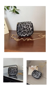 Detailed view of the leopard print saddle bag with a golden chain strap on a wooden desk