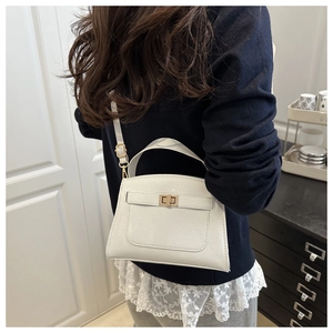 Detail of white lychee pattern trapezoid bag with gold twist lock on female model