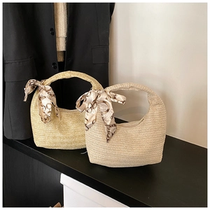 Detailed close-up of woven straw crescent bags featuring elegant chain-print silk scarves