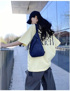 Detail of navy blue waterproof nylon chest bag featuring adjustable strap and orange label