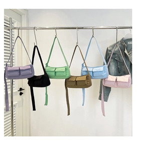 Row of colorful nylon crossbody bags with dual front pockets hanging on a white wall
