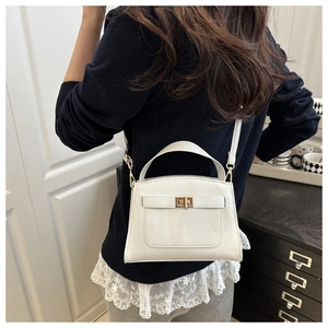 White textured leather trapezoid handbag worn crossbody in a cozy home setting