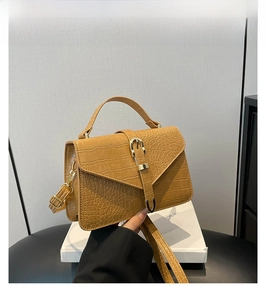 Détail d'un sac à main marron texture crocodile avec boucle dorée et poignée supérieure