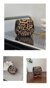 Detail showing leopard print saddle bag with gold chain strap on a rustic table