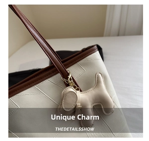 Close-up of cream pebble leather tote with brown strap and cute puppy pendant detail