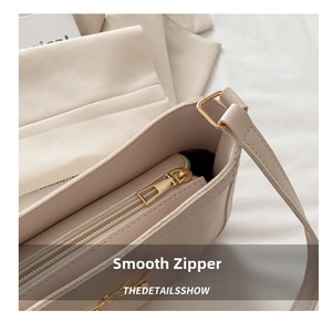 Detail view of smooth metal zipper and adjustable buckle on cream bow shoulder bag