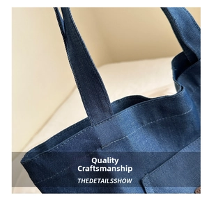 Detailed close-up of double-stitched denim straps on a dark blue fashion tote bag