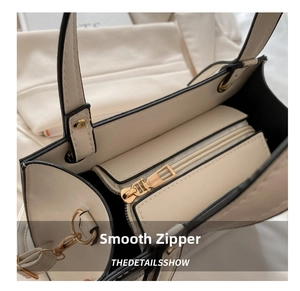 Detailed close-up of premium gold hardware and smooth zipper on a beige handbag