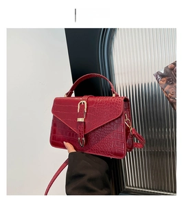 Détail du sac à main rouge texture crocodile avec boucles dorées et bandoulière chic