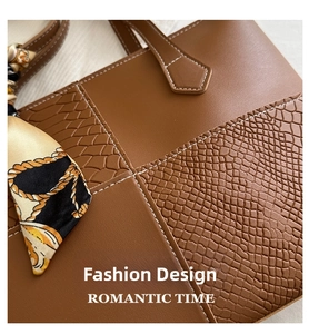 Detail of brown leather tote with crocodile embossing and patterned silk scarf accent