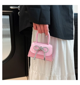 Détail d'un mini sac rose avec un nœud en strass étincelant et une bandoulière chaîne