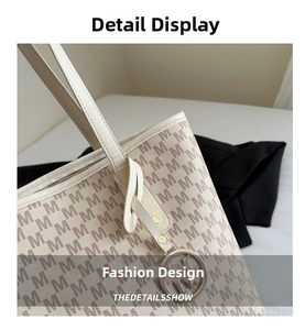 Close-up of off-white tote bag featuring M-letter print and gold metal logo charm