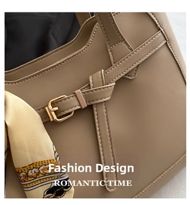 Detail of khaki leather tote bag featuring a silk scarf wrap handle and gold metal hardware