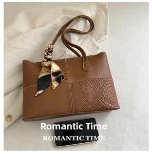 Detail of brown tote bag with snake print panels, silk scarf handle, and phone size comparison