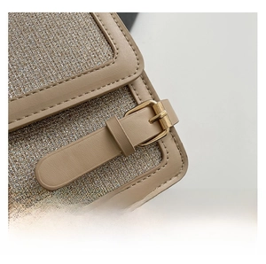 Close-up of glitter fabric texture with khaki leather trim and gold buckle detail