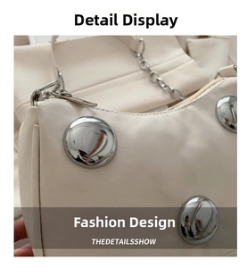 Detailed close-up of beige handbag featuring large silver metal studs and sleek chain strap